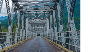 Blick auf das Ende einer Stahlbrücke, aufgenommen vom Anfang der Brücke, mit der Struktur des Stahlrahmens deutlich sichtbar.