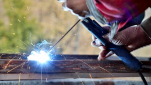 Schweißer bei der Arbeit an wetterfestem Stahl im industriellen Umfeld